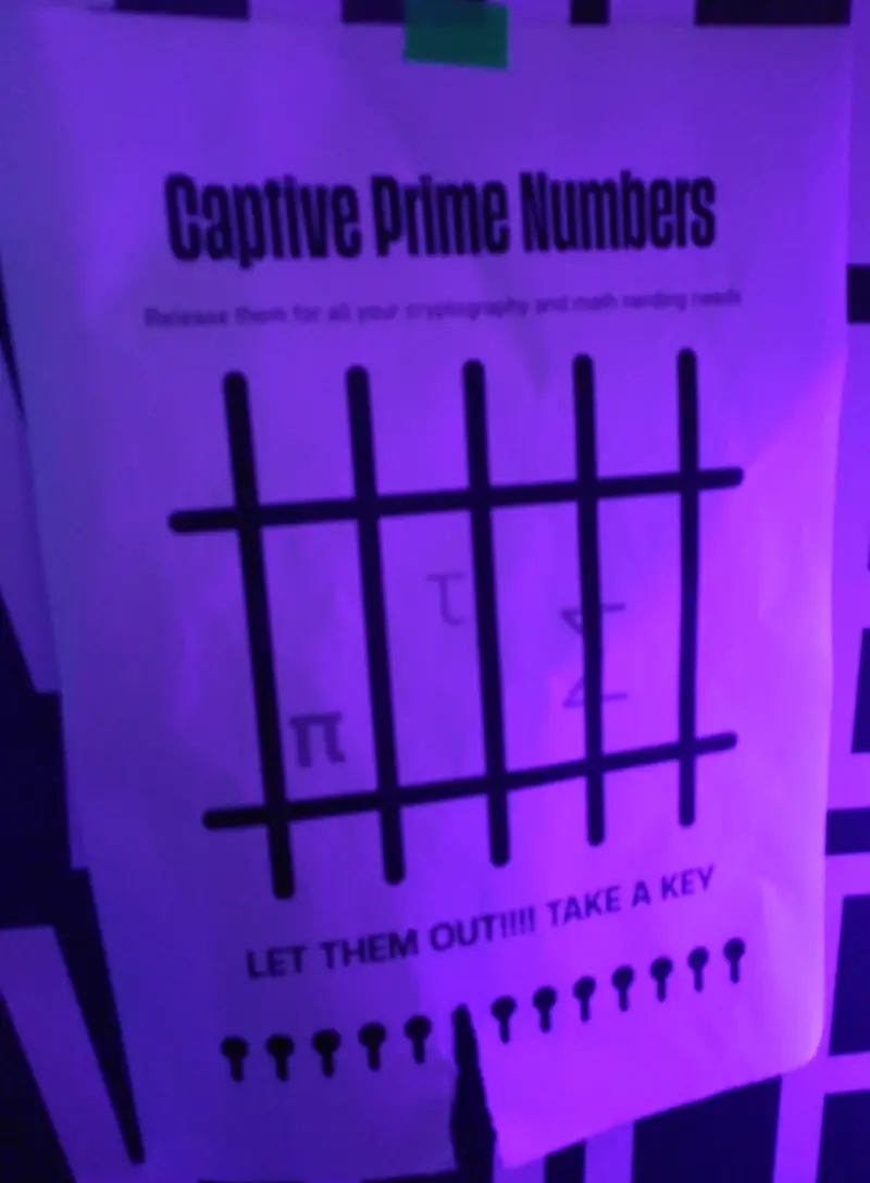 Ein Papieraushang ähnlich dem ersten Aushang, allerdings mit dem Titel „Captive Prime Numbers“. π, τ und Σ sind hinter Gittern dargestellt. darunter der Satz „LET THEM OUT!!!! TAKE A KEY, und darunter Bilder von Schlüsseln zum abreißen.