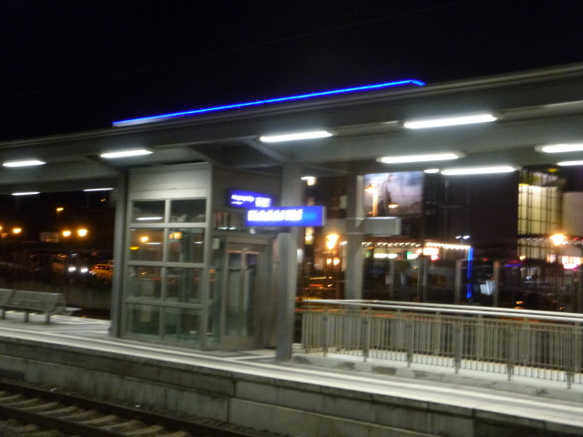 Ein Bahnsteig bei Nacht. Das Namensschild ist so verschwommen, dass man es kaum lesen kann.