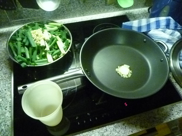 schmelzende Butter in einer Pfanne, daneben Frühlingszwiebeln und Wasser