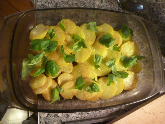 Kartoffelscheiben, bedeckt mit Basilikum in einer Auflaufform