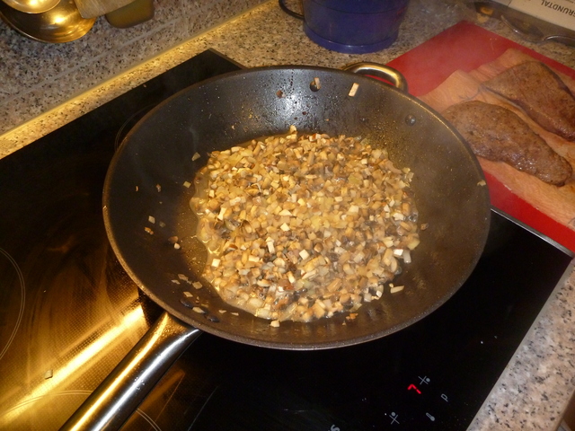 Geschnittene Champignons und Schalotten in einer Pfanne