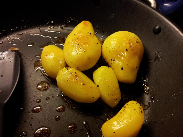 Die Kartoffeln am Stück in einer Pfanne. Sie glänzen undsind gesprenkelt mit Pfeffer