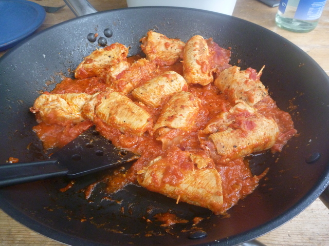 bratende Putenröllchen in Tomatensoße in der Pfanne mit geringerem Flüssigkeitsanteil