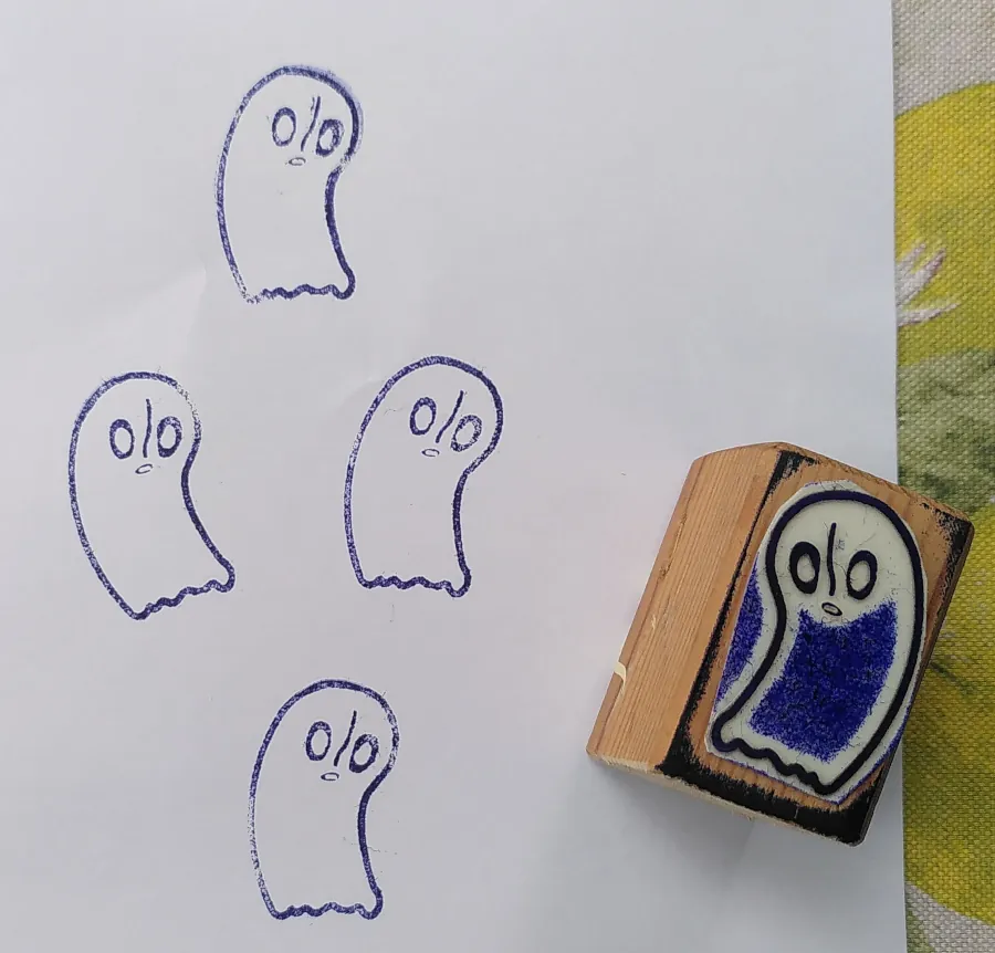 Vier Stempelabdrücke von Napstablook in blauer Farbe auf weißem Papier. Daneben mit dem Motiv nach oben der dazugehörige Stempel